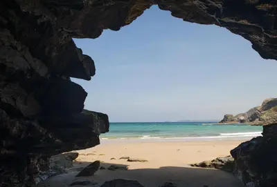 a view of the beach through a rock formation at Castaways in Porthtowan