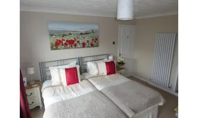 a bedroom with two beds with red and white pillows at Seven Bed and Breakfast in St. Agnes