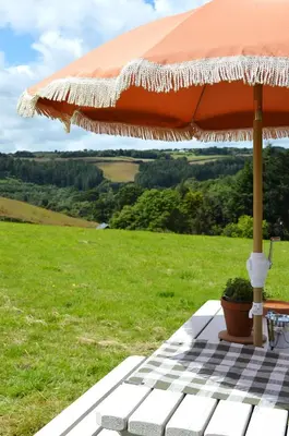an orange umbrella sitting on top of a picnic table at Tylda Tents at Heydaze Campsite - 5m Luxury Bell Tent 