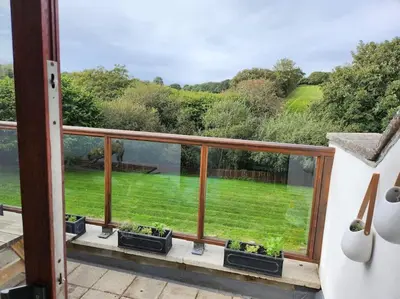 a balcony with a view of a green yard at Cornwall Truro Falmouth cottage in Perranwell