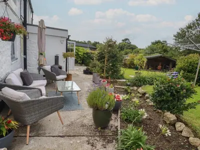 a garden with chairs and flowers in a yard at Bumblebee Cottage in Bodmin