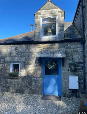 a stone house with a blue door and two windows at Stunning 4 Bed Pet Friendly Cottage with Hot Tub in Bodmin