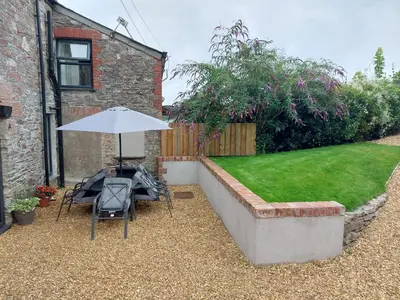 a patio with a table and an umbrella and a lawn at Swallows Rest Cottage - 3 Bedrooms - Nr Looe in Looe