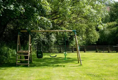 a swing set in a park with a grass field at Rainbow Cottage in Liskeard