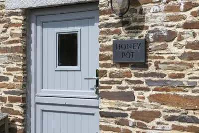 a white door with a honey pot sign next to a brick building at Honey Pot in Liskeard