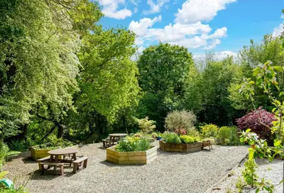 a garden with tables and benches and trees at Blackberry Barn in Liskeard