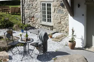 a patio with a table and chairs in front of a building at Worvas Counthouse - Country Cottage - Hot Tub - Pet Friendly in St Ives
