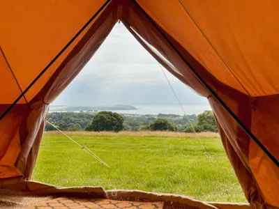 an orange tent with a view of a field at Furnished Bell Tent 1 in St Austell