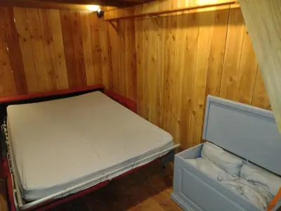 a small bed in a room with wooden walls at Tiny House Glamping, sleeps up to 6 in Gweek