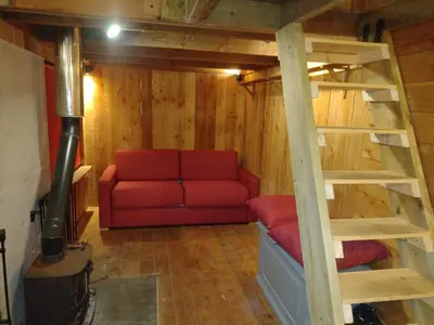 a living room with a red couch and a ladder at Tiny House Glamping, sleeps up to 6 in Gweek