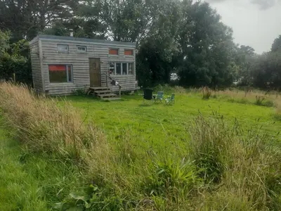 a small house in a grassy field at Tiny House Glamping, sleeps up to 6 in Gweek