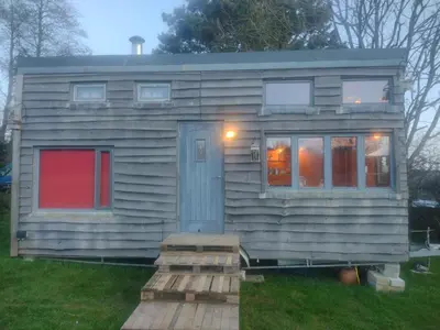 a tiny house sitting on top of a field at Tiny House Glamping, sleeps up to 6 in Gweek