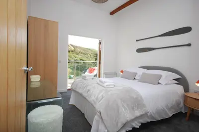 a white bedroom with a bed and a window at Anemone in Porthtowan