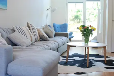 a living room with a couch and a table with a vase of flowers at Anemone in Porthtowan