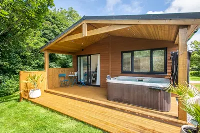 a hot tub on a deck in a backyard at Maple Lodge in Hayle