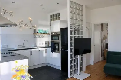 a kitchen with white cabinets and a black refrigerator at Flip Flop Flat, Sea Views, Short Stroll to Beaches in Newquay