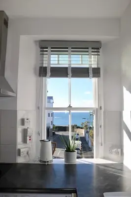 a kitchen with a window with a view of the ocean at Flip Flop Flat, Sea Views, Short Stroll to Beaches in Newquay
