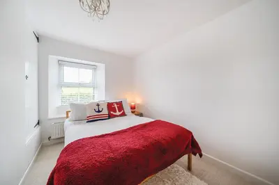 a white bedroom with a bed with a red blanket at Fowey, quaint cottage near sea in Fowey
