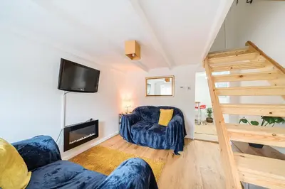 a living room with a staircase and a couch and a television at Fowey, quaint cottage near sea in Fowey