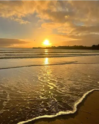 a sunset on a beach with the ocean at The Lobster Pot in Tywardreath