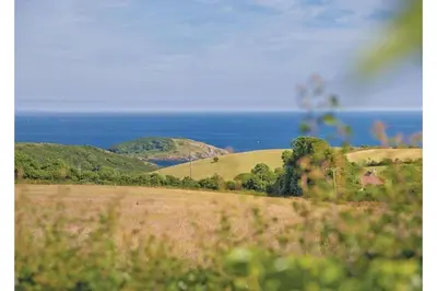 a view of a field with the ocean in the background at Tencreek Holiday Park in Looe