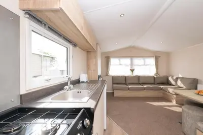 a kitchen and living room with a stove and a couch at Tencreek Holiday Park in Looe