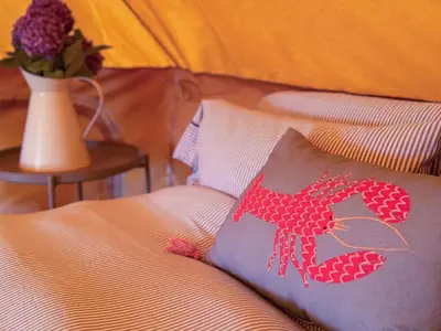 a bed with a pillow with a red lobster on it at Furnished Bell Tent 3 in Carlyon Bay