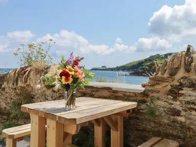 a vase of flowers sitting on a wooden table at Chy Rani in Portmellon