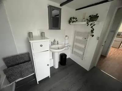 a white bathroom with a sink and a mirror at 1 Carnebone Cottages in Porkellis