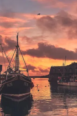 a boat sitting in the water at sunset at Holiday Home Elm Cottage by Interhome in Mevagissey