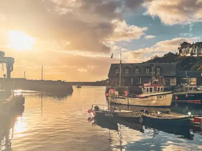 a group of boats docked in a harbor with the sunset at Holiday Home Elm Cottage by Interhome in Mevagissey