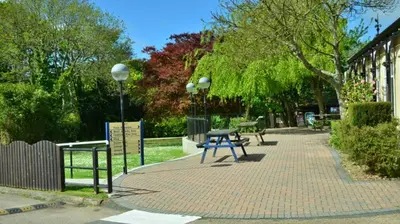 a picnic table on a brick sidewalk next to a building at 06 Strawberry Hill, Tolroy Manor in Hayle