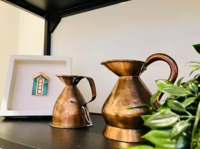 two copper vases sitting on a table next to a picture at The Cuckoo's Retreat - Luxurious home with private garden & jacuzzi in Kenwyn