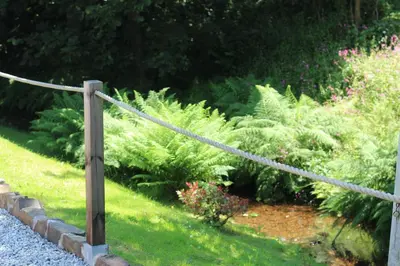 a garden with a wooden fence and some plants at The BarnsPigallie in Redruth