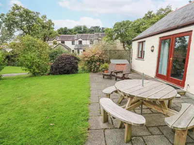 a patio with a wooden table and benches at Chy Lowena in Falmouth