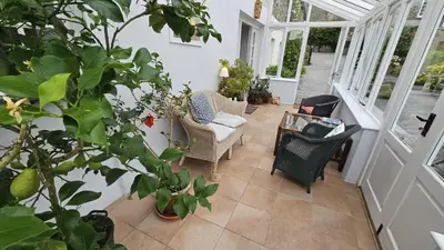 a porch with chairs and a table and plants at Glebe Barn in Ruan Lanihorne
