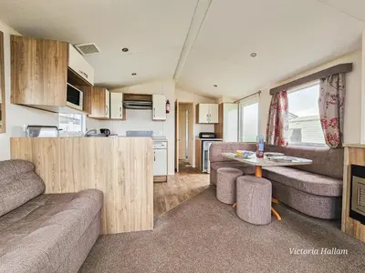a living room with a couch and a table in a caravan at Summer Breeze in Perranzabuloe