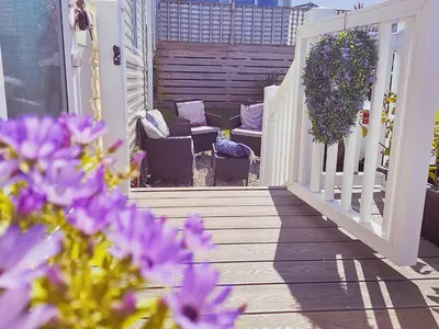 a porch with chairs and purple flowers on a house at Summer Breeze in Perranzabuloe