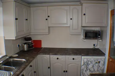 a kitchen with white cabinets and a sink and a microwave at Itldo in Truro