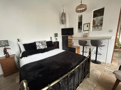 a bedroom with a black and white bed and a fireplace at Thea Cottage in Perranuthnoe