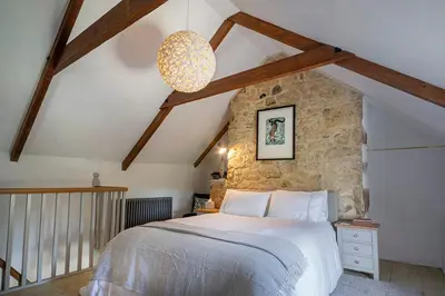 a bedroom with a bed and a stone wall at Manor Cottage at Cusgarne Manor, romantic, dog-friendly in Cusgarne