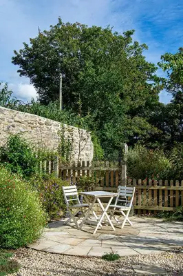 two chairs and a table in front of a fence at Manor Cottage at Cusgarne Manor, romantic, dog-friendly in Cusgarne