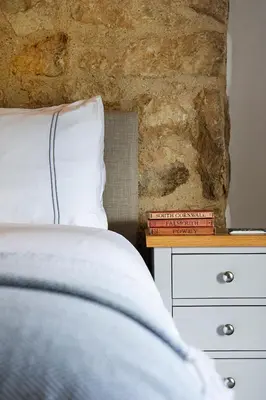 a bedroom with a bed and a stone wall at Manor Cottage at Cusgarne Manor, romantic, dog-friendly in Cusgarne
