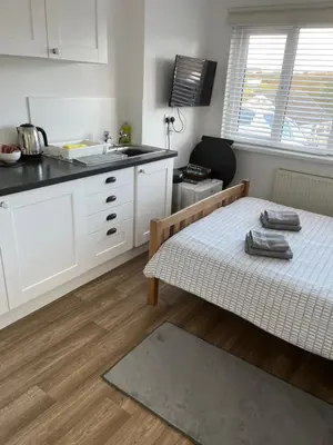 a kitchen with white cabinets and a table in a room at Hellfire corner in Redruth