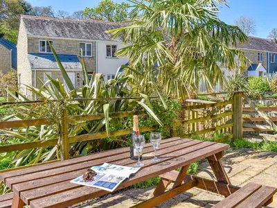 a wooden picnic table with a bottle and two glasses at Dreckly in Falmouth