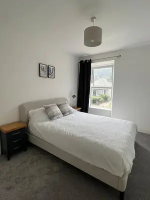 a bedroom with a white bed and a window at The Cove, Portreath in Portreath