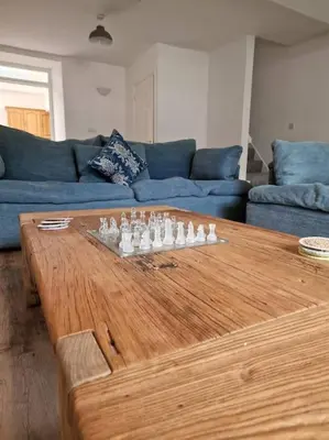 a living room with a wooden table with chessetts on it at The Cove, Portreath in Portreath