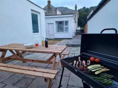 a grill with vegetables on it next to a picnic table at The Cove, Portreath in Portreath