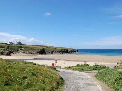 a dirt road leading to a beach with the ocean at Scrumpy Cottage in Bodmin