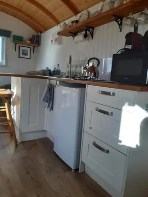 a kitchen with white cabinets and a white refrigerator at The Shepherd Hut in Carleen